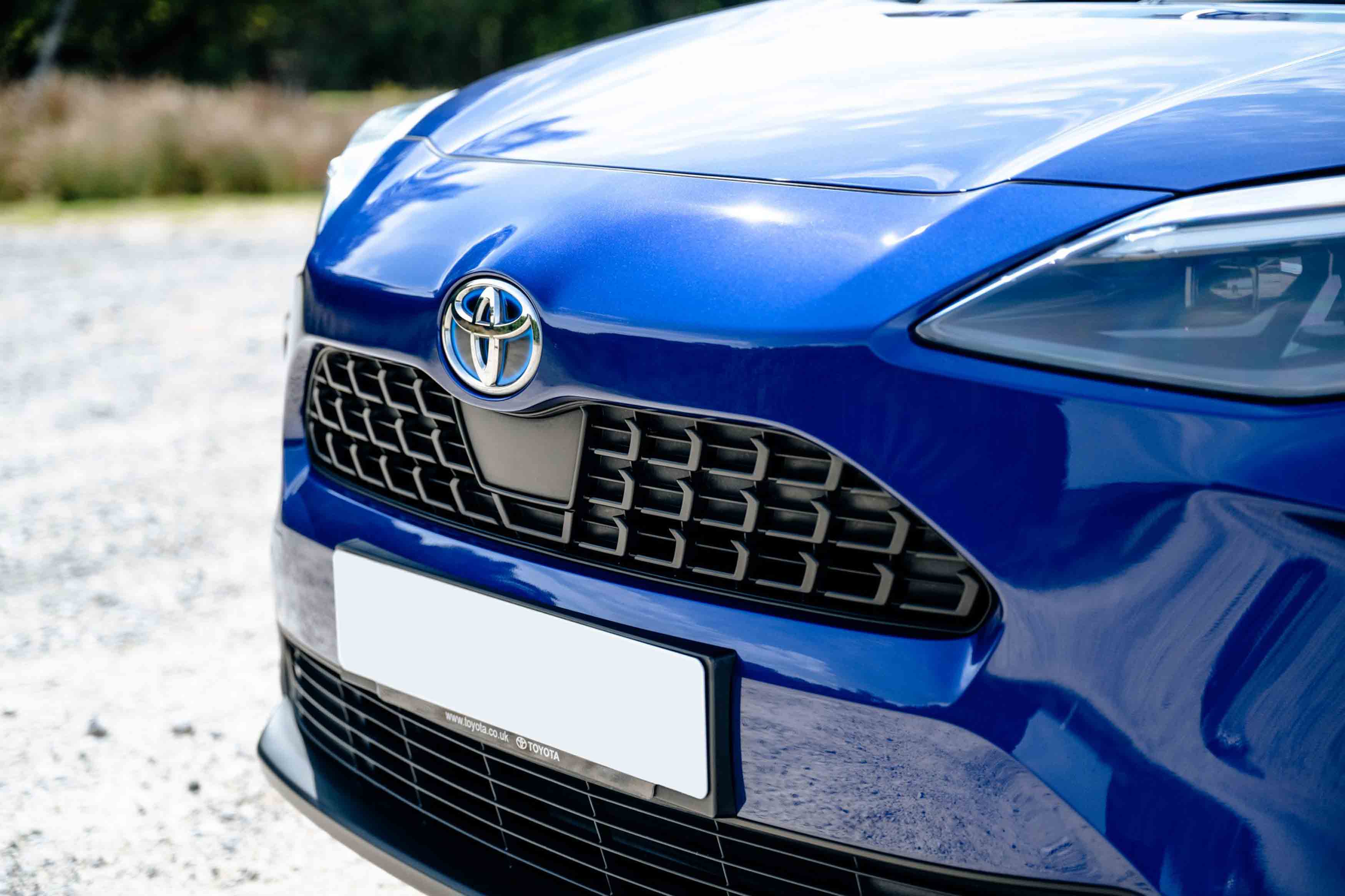 Front grille and Toyota logo of a blue Toyota vehicle, highlighting the distinctive mesh pattern